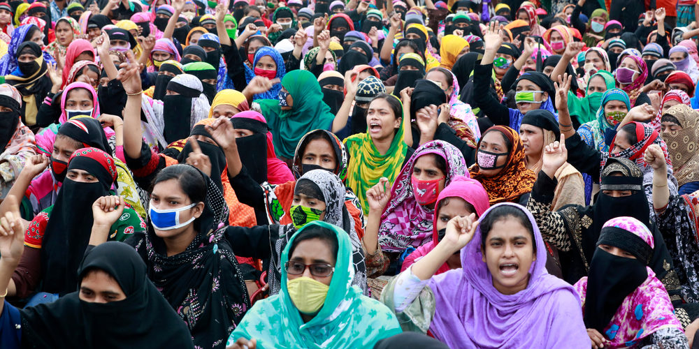 Garment workers in a crowd, many hands raised.